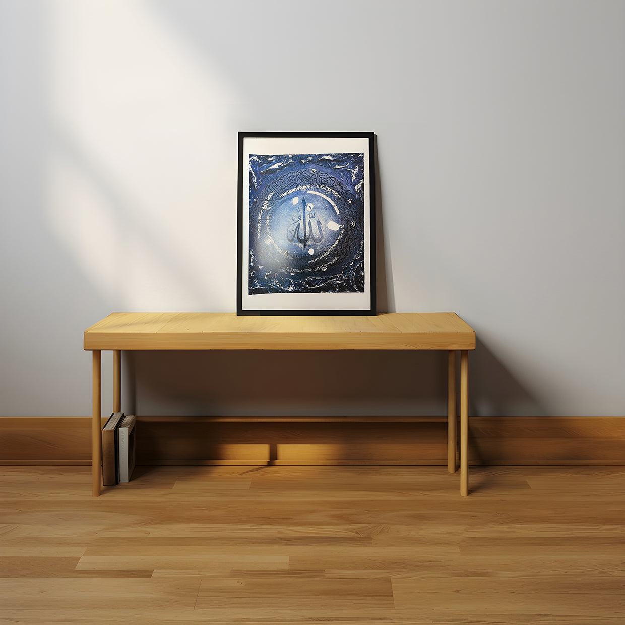 Framed artwork on a wooden table against a plain wall