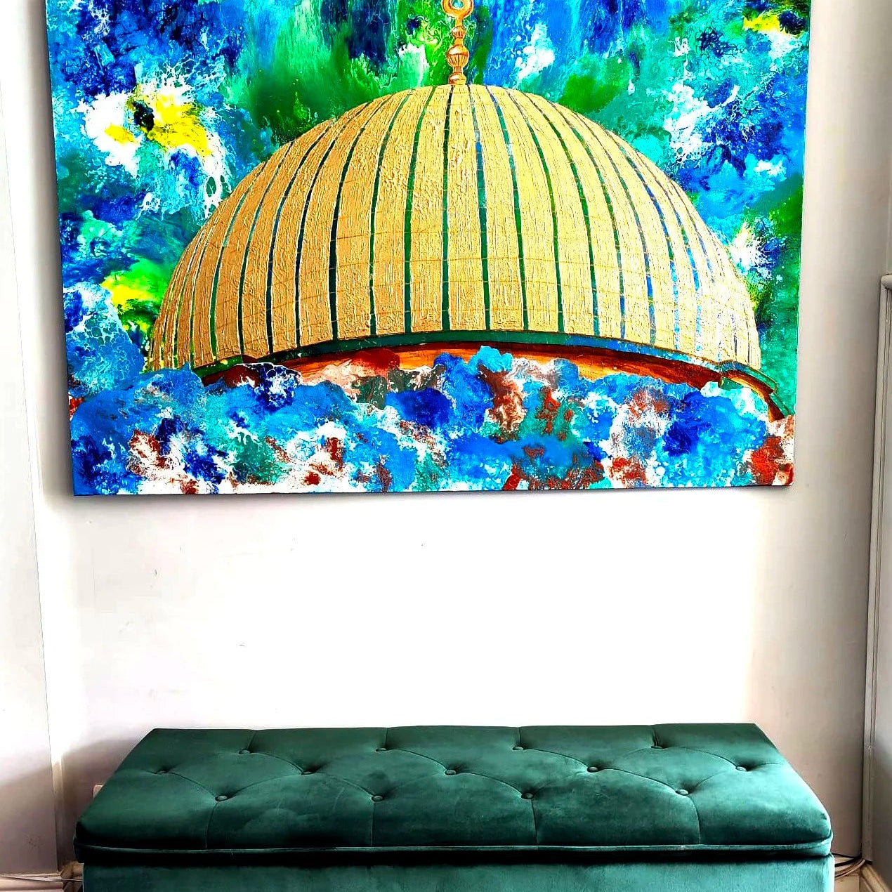 Colorful abstract painting of a domed structure on a wall above a green bench.
