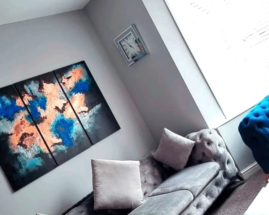 Living room with a gray sofa, colorful abstract art on the wall, and a chandelier.