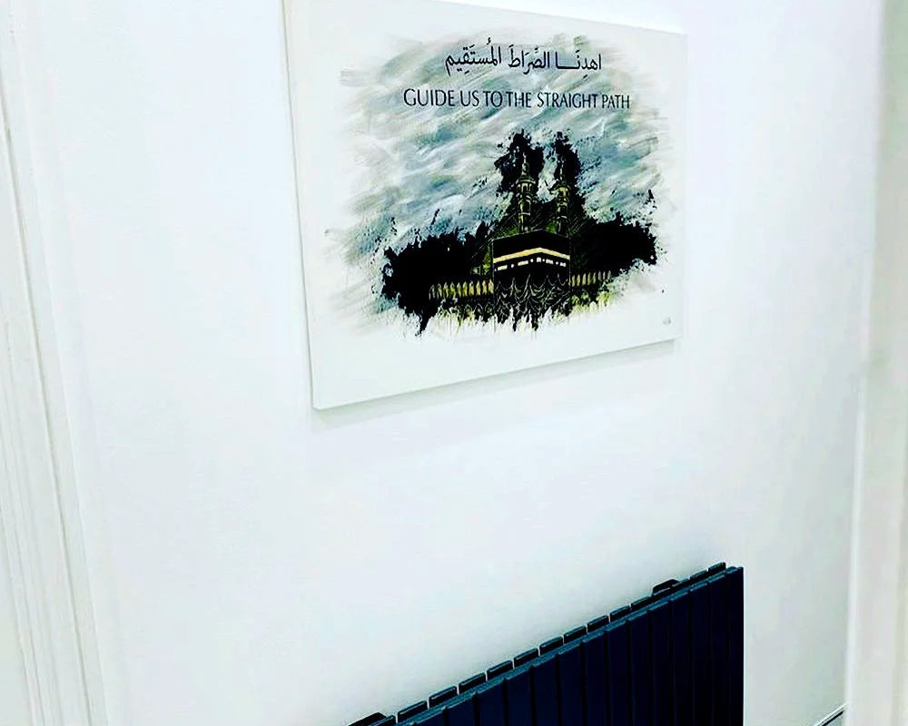Decorative wall art with Arabic text and a silhouette of a mosque on a white wall.