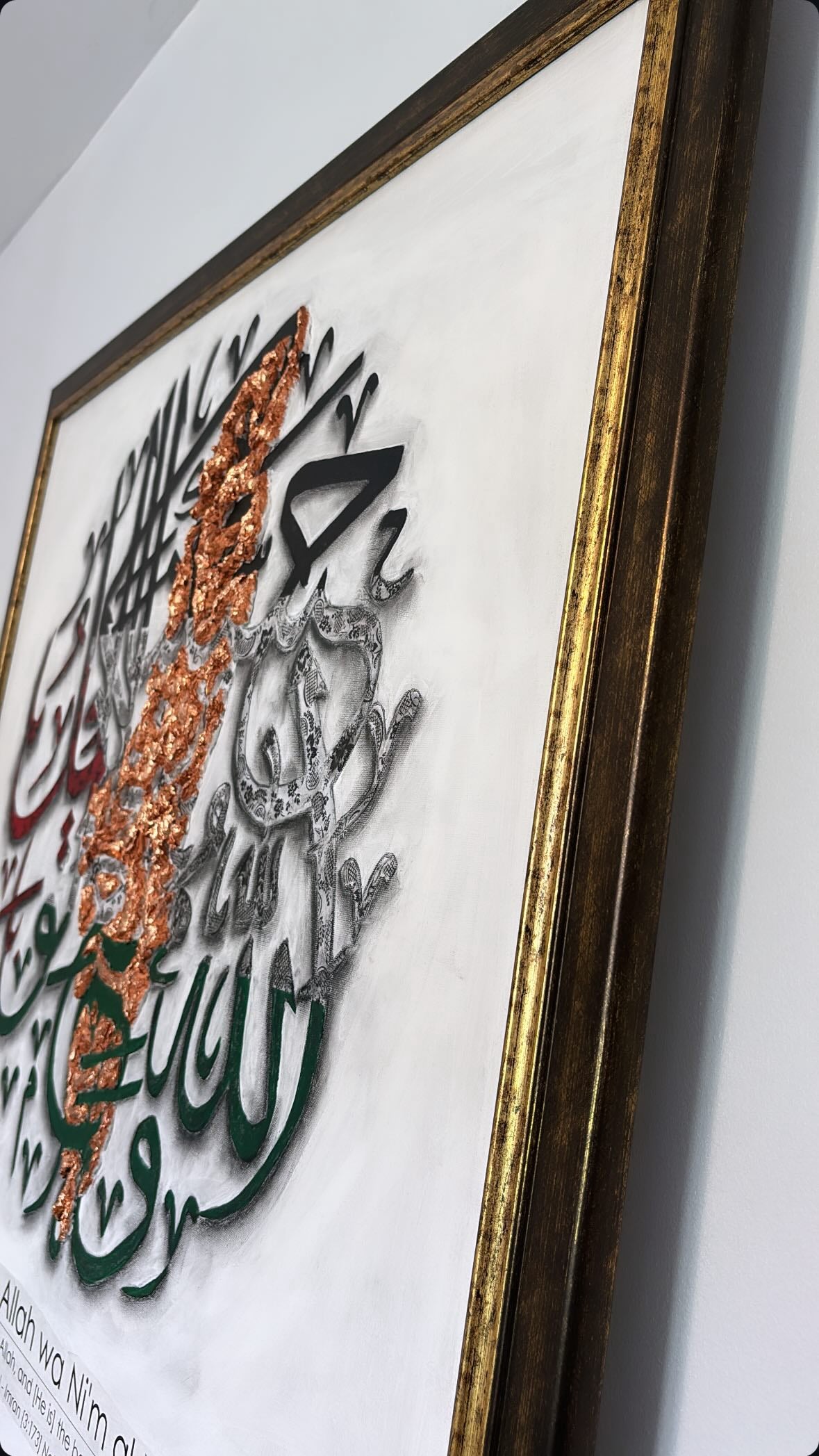 Decorative wall art with Arabic calligraphy and a gold frame.