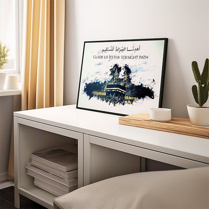 Framed artwork on a desk with a plant and books in a room.