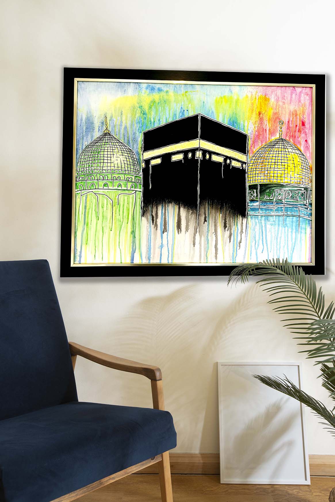 Framed artwork of a religious building with colorful abstract design on a wall above a blue chair.